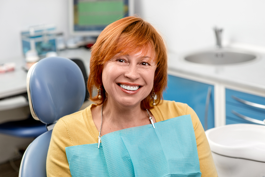 red haired senior woman smiling in chair at dentist Old Bridge, NJ dental implants